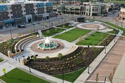 An aerial view of the courtyard at the District at Prairie Trail in Ankeny that features an artistic brick inlay, a stone water fountain, and green spaces.