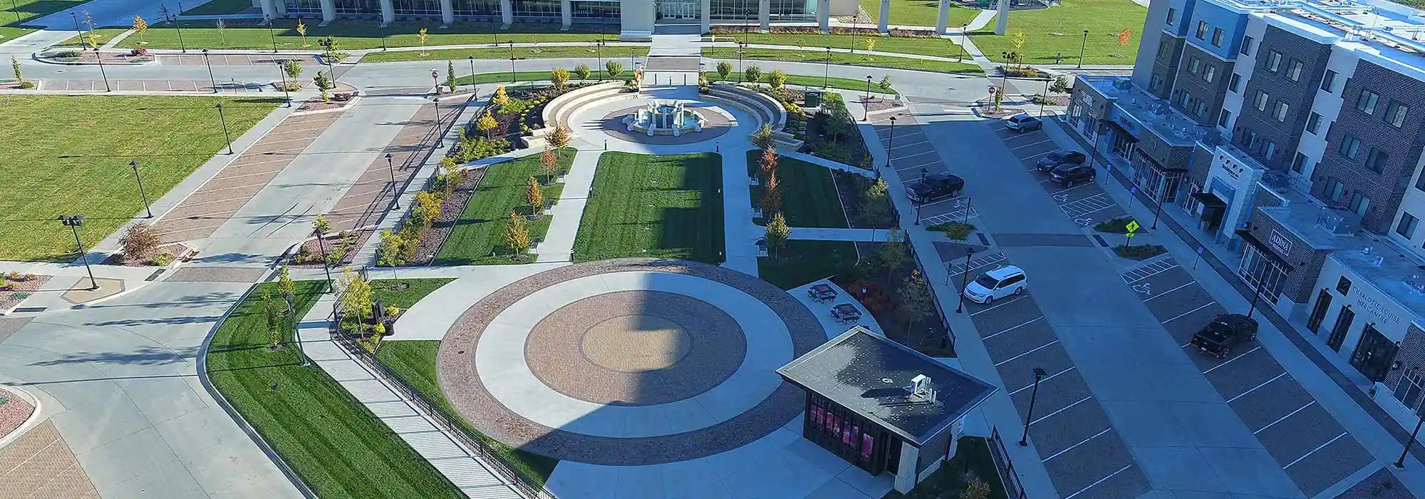 An aerial view of the courtyard in the District at Prairie Trail in Ankeny that features an artistic brick inlay, a stone water fountain, and green spaces.